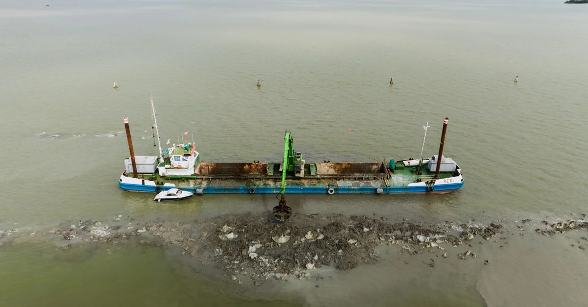 Luftaufnahme von einem Bagger-Boot in der Lagune von Venedig, das Erdarbeiten durchführt.