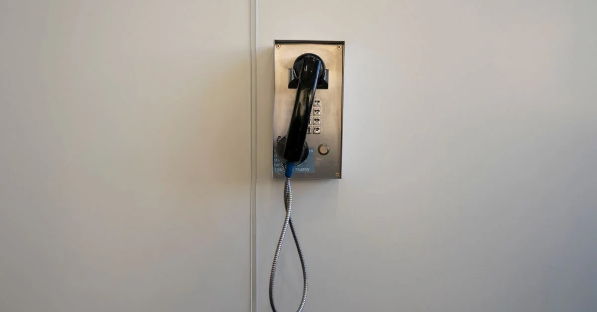Eine vintage, wandmontierte Telefonzelle in einem minimalistischen Umfeld, die retro Technologie zeigt.