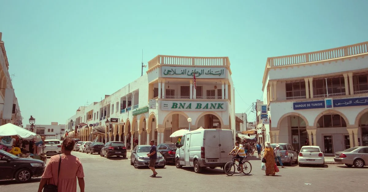 Eine lebendige Straßenszene in Tunis mit der ikonischen BNA-Bank und lokalen Menschen, die zu Fuß oder mit dem Fahrrad unterwegs sind.