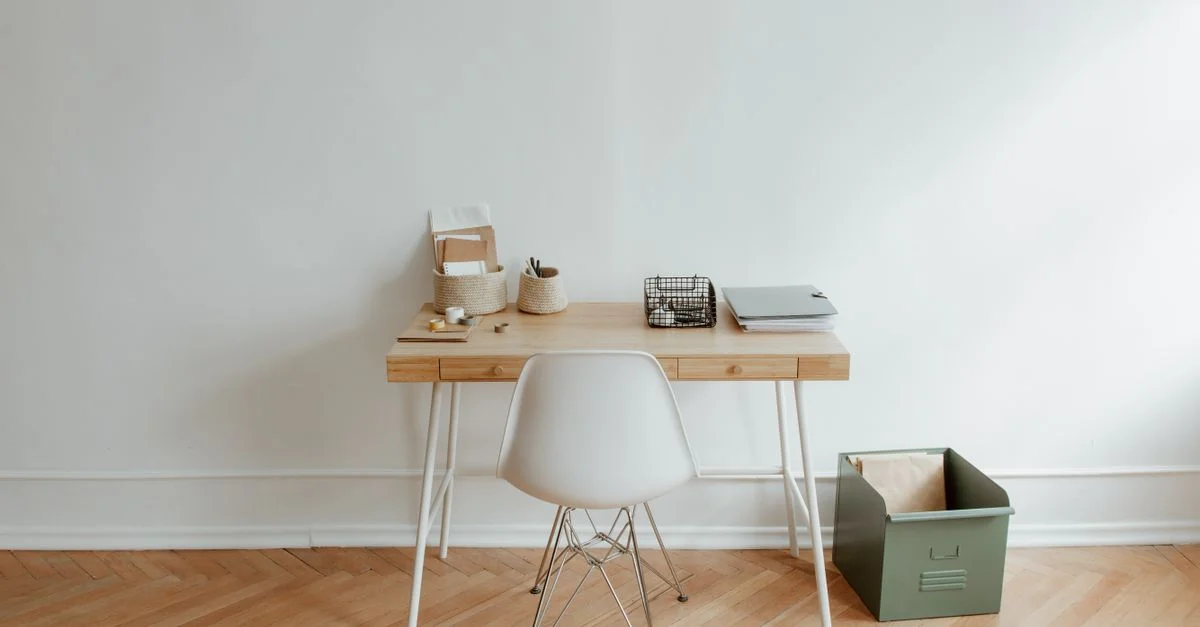 Ein minimalistisches Homeoffice-Setup mit einem Holztisch und einem weißen Stuhl, das eine saubere und einfache Ästhetik bietet.