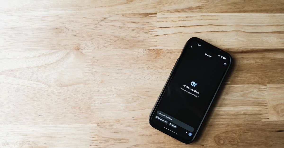 Draufsicht auf ein Smartphone, das eine Chatbot-Schnittstelle auf einer hellen Holzoberfläche anzeigt.