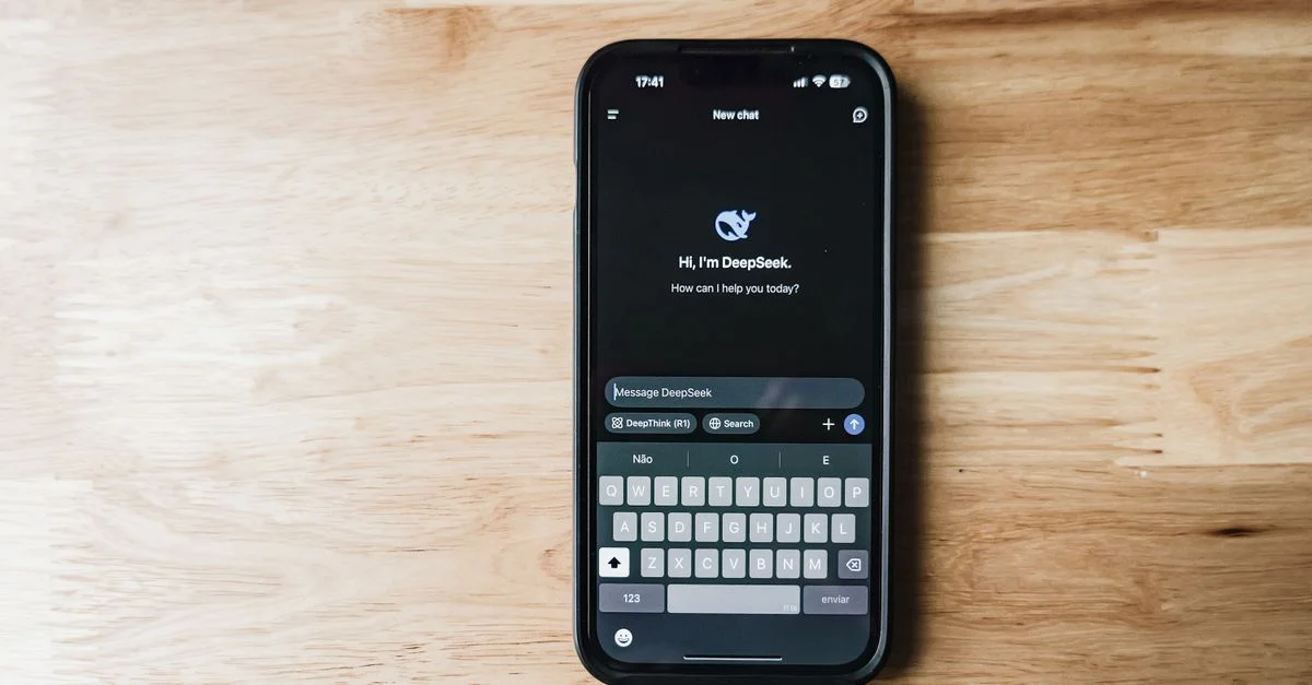 Ein Smartphone auf einem Holztisch, das eine KI-Chatbot-Schnittstelle namens DeepSeek zeigt.