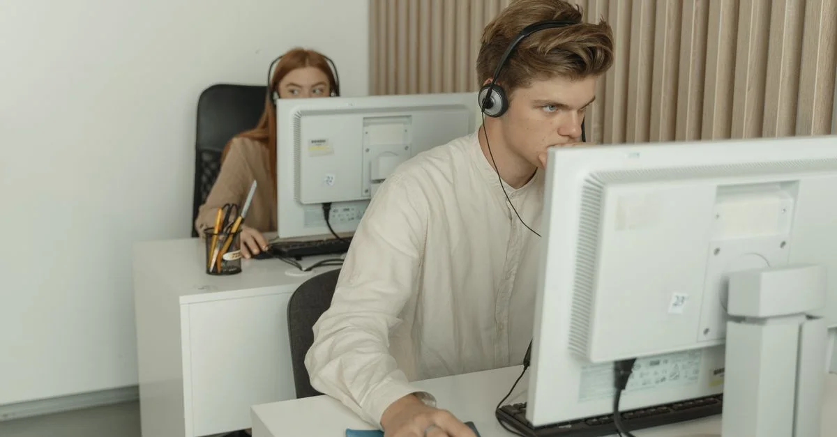 Zwei junge Fachleute, die fleißig an Computern in einem modernen Büro arbeiten.
